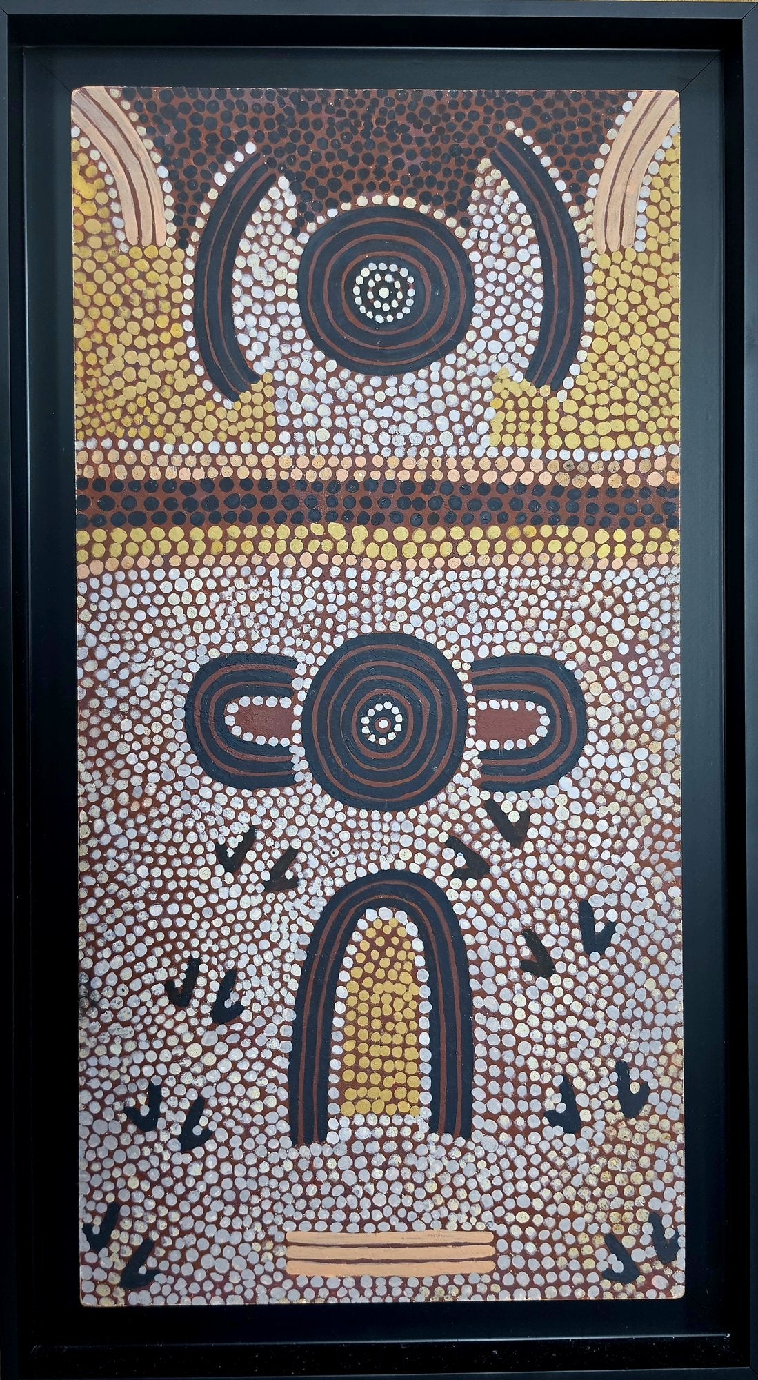 Vertical dot painting in ochre, cream and brown showing two stacked concentric-circle motifs flanked by curved forms, above a golden arched shape on a densely dotted ground.