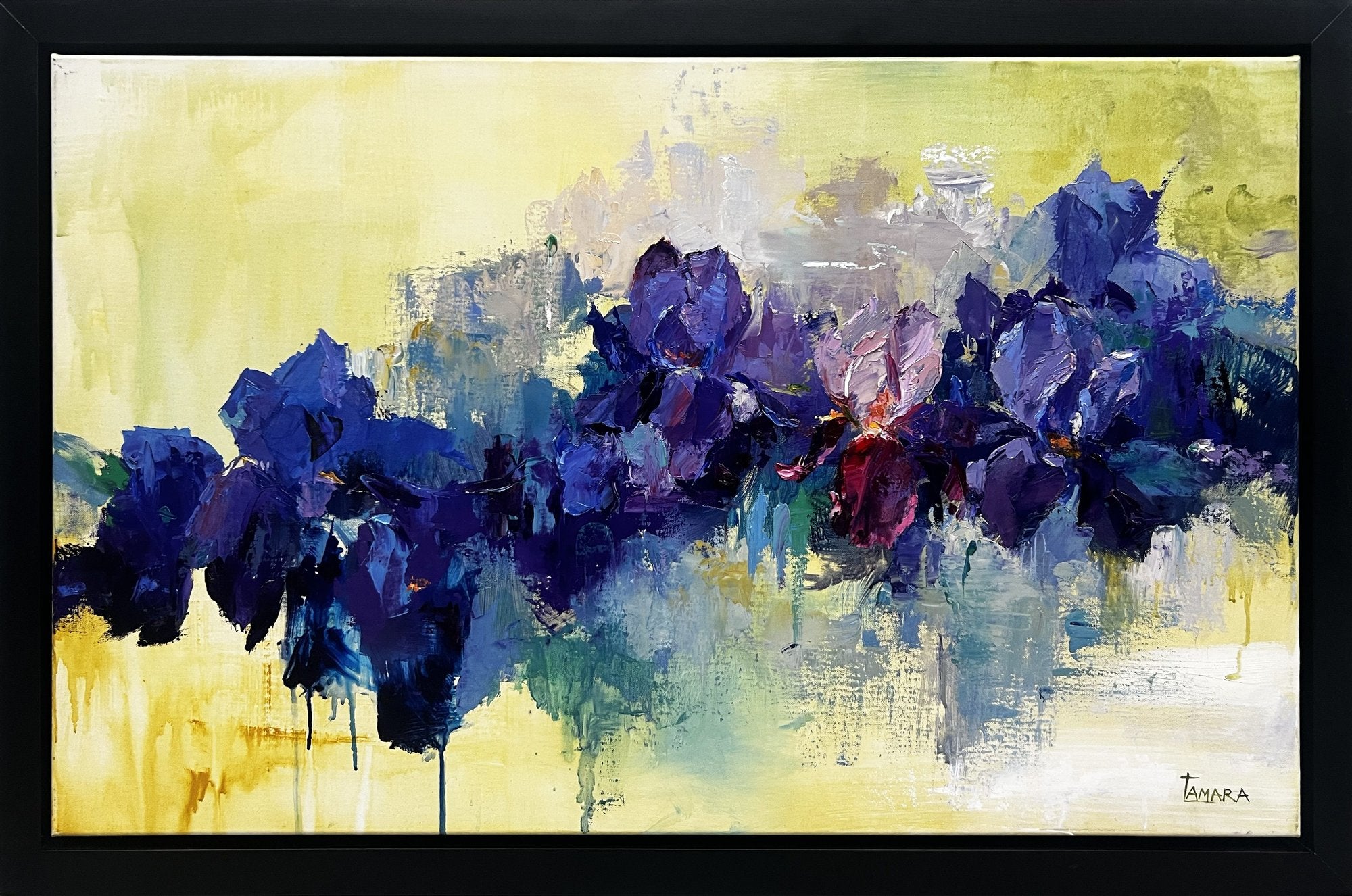 Horizontal painting of indigo and violet irises in heavy palette knife impasto, set against a pale yellow background with paint drips and a soft reflection below.