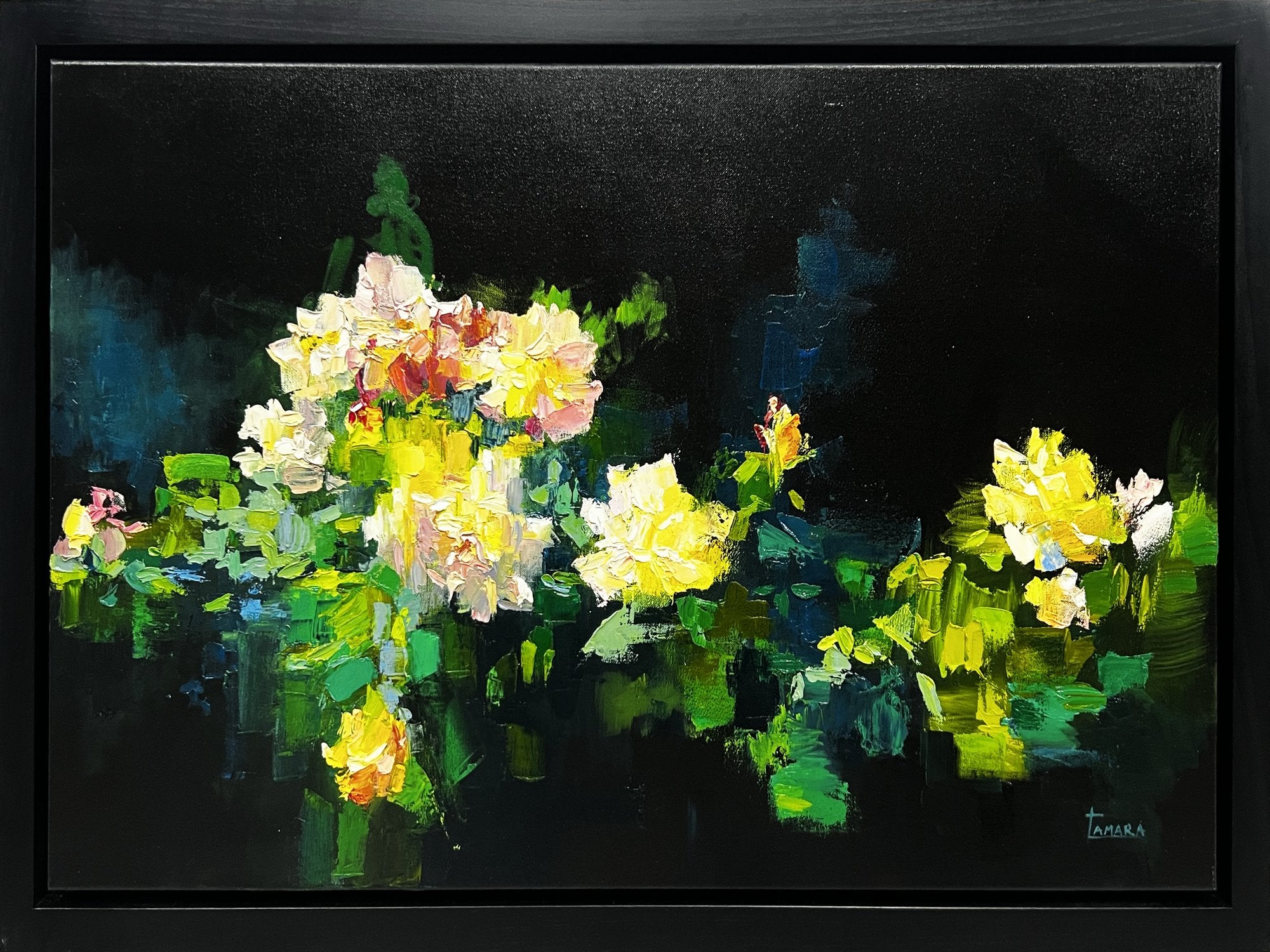 A framed oil painting of yellow, cream and pink roses built in thick palette knife strokes, set against a deep black background with green foliage and reflections below.